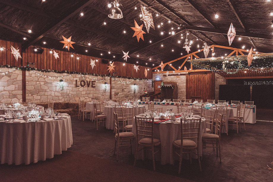 Inside barn tables decorated for a wedding with fairy lights and stars