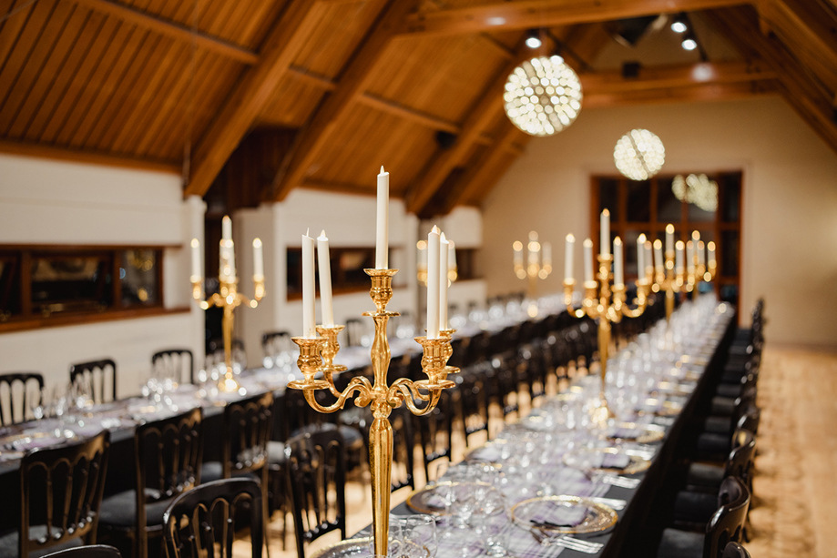 Close-up of elegant wedding reception tables at Edinburgh Castle with gold candelabras, glassware and black linen styling.