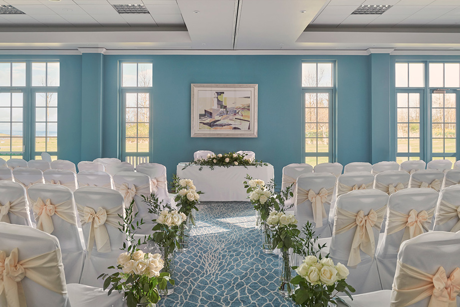 Small blue ceremony room with cream flowers lining the aisles