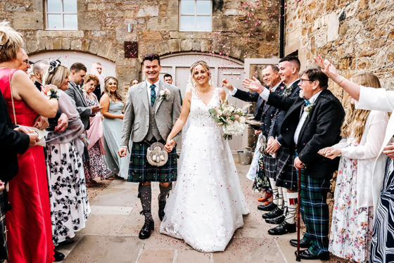 Guests celebrate following wedding ceremony with bride and groom smiling