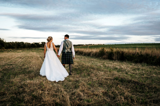 Bride and groom walk through field