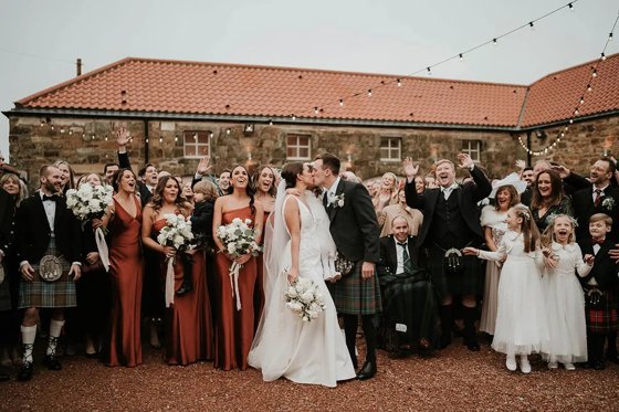 Bride and groom kiss in front of guests in venue Courtyard