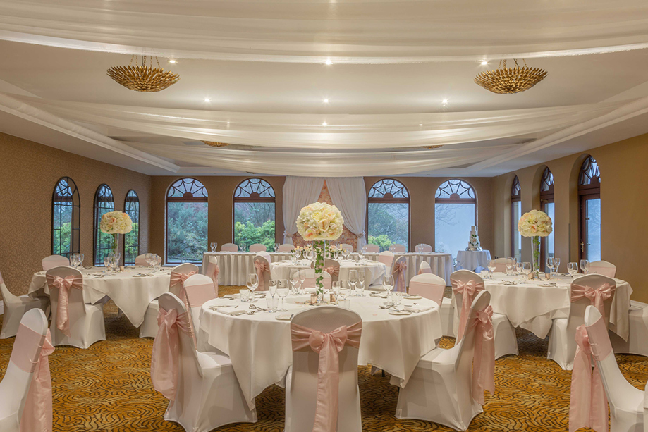 Wedding meal set up with cream rose bouquet centrepieces and pink bows on chairs