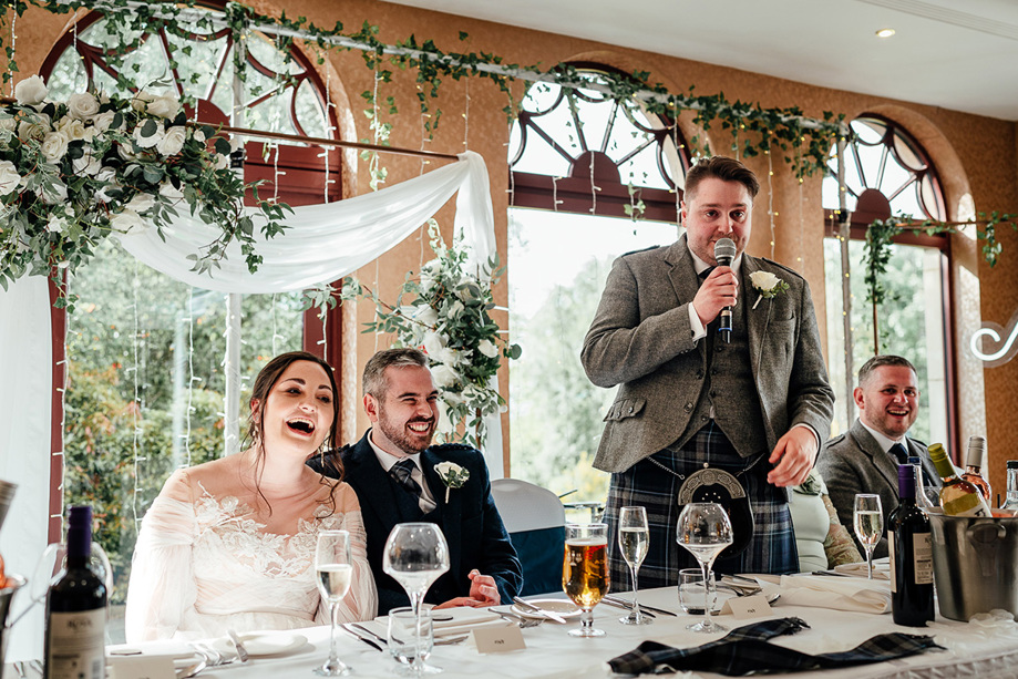 Bride and groom laugh as best man makes his speech