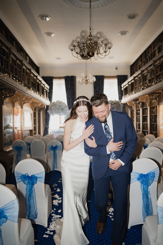 Bride and groom laugh as they walk back up aisle at 1599 at the Royal College.