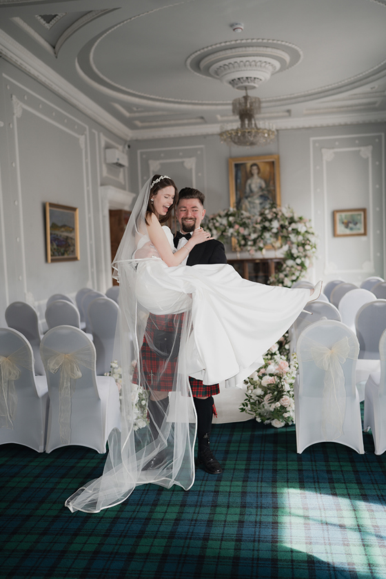 Groom carries bride back up the aisle at 1599 at the Royal College.