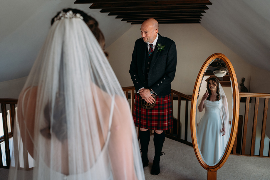 Father of the bride first look at Harelaw Farm in Ayrshire with reflection in wooden mirror.