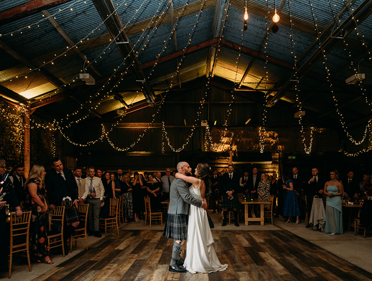 Bride and groom's first dance at Harelaw Farm in Ayrshire, beneath draped fairy lights and guests watching on in background.