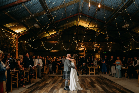 Bride and groom's first dance at Harelaw Farm in Ayrshire, beneath draped fairy lights and guests watching on in background.