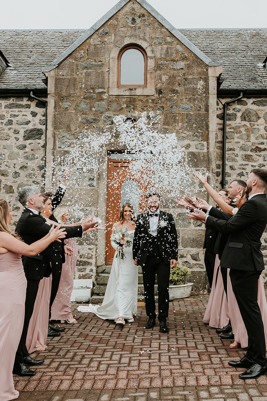 Newlyweds walk through confetti toss in courtyard of Harelaw Farm.