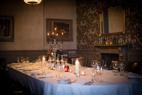 Intimate candlelit wedding meal at Hotel du Vin St Andrews, with candelabra in centre of long table.