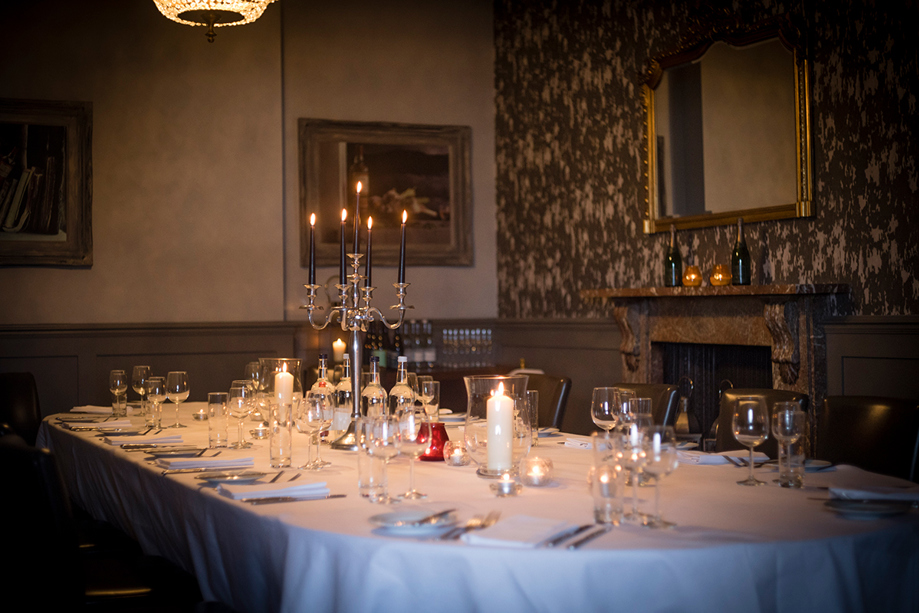 Intimate candlelit wedding meal at Hotel du Vin St Andrews, with candelabra in centre of long table.