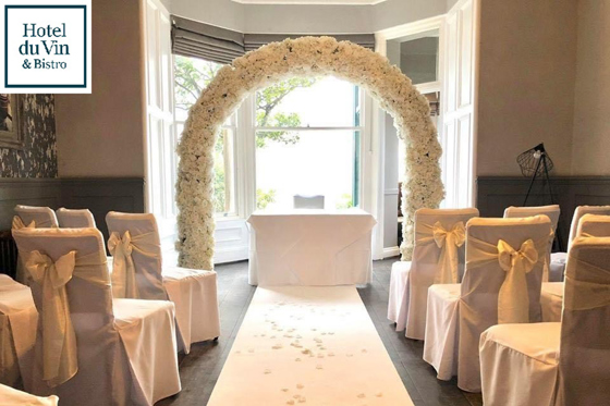 Wedding ceremony at Hotel du Vin St Andrews with white floral arch at altar.