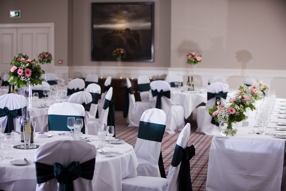 Swilcan Suite wedding meal set up at Hotel du Vin St Andrews with floral bouquets on round tables and navy chair sashes.