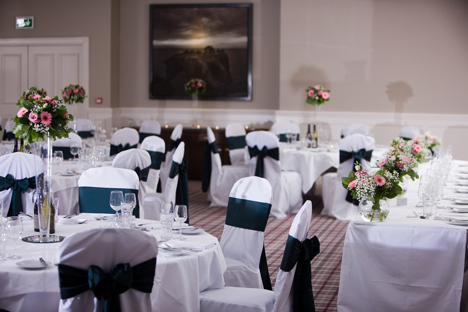 Swilcan Suite wedding meal set up at Hotel du Vin St Andrews with floral bouquets on round tables and navy chair sashes.