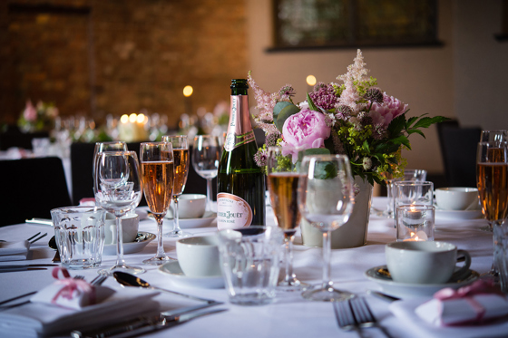 Glasses on table with champagne and pink flowers