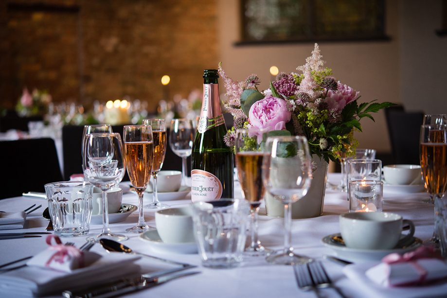Glasses on table with champagne and pink flowers