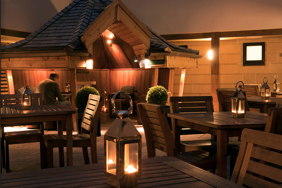 Outdoor seating in cabin with candlelit lanterns on outdoor tables