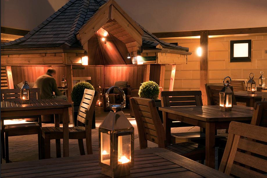 Outdoor seating in cabin with candlelit lanterns on outdoor tables