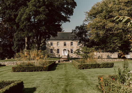 Exterior of country house wedding venue, House of Elrick, on Elrick Estate in Aberdeenshire. Blue skies in background and lush manicured gardens in foreground.