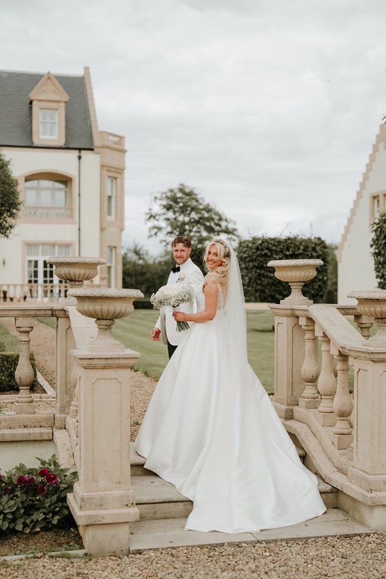 Bride and groom posing on stone staircase at Ingliston Estate and Country Club wedding venue in Glasgow