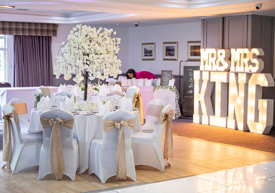 Mr & Mrs King lights in room with white and gold decor and tree centrepiece