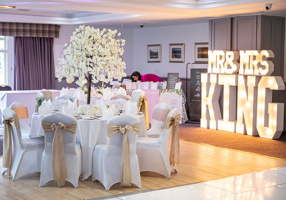 Mr & Mrs King lights in room with white and gold decor and tree centrepiece