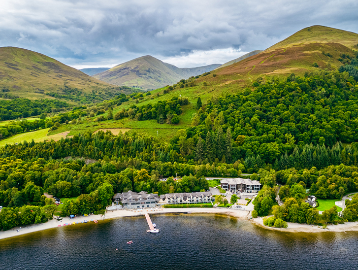 Lodge on Loch Lomond drone image showing woodlands and hills beyond the Loch Lomond wedding venue.