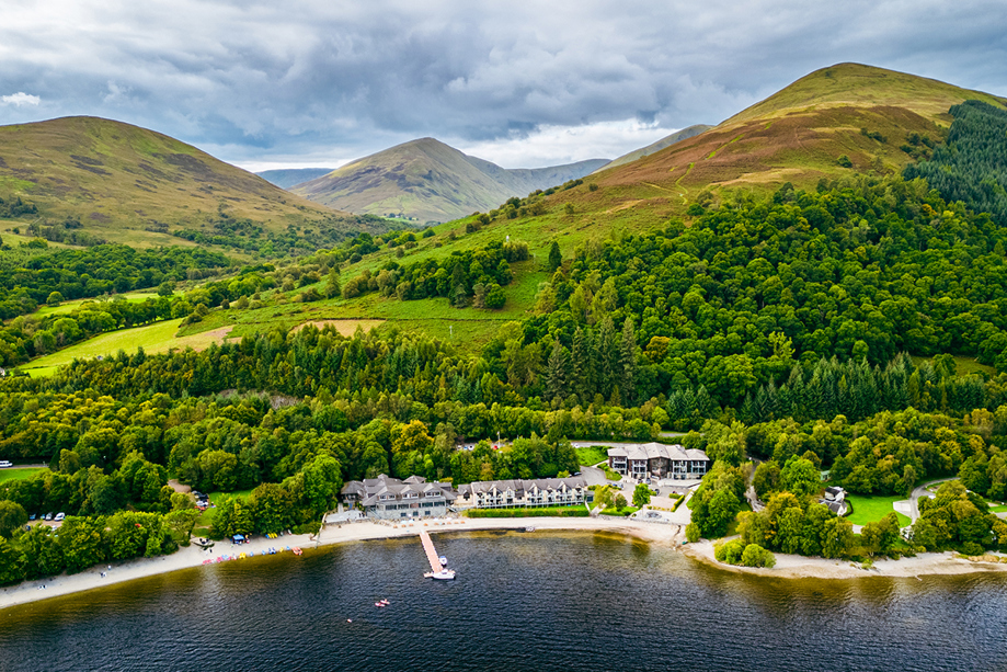 Lodge on Loch Lomond drone image showing woodlands and hills beyond the Loch Lomond wedding venue.