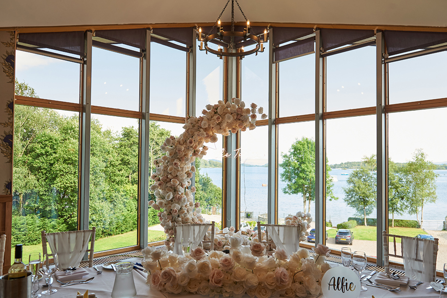 Moon-shaped flower arch behind top table at wedding meal.
