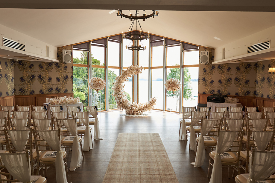 Ceremony set up at Lodge on Loch Lomond with moon-shaped floral arch at altar.