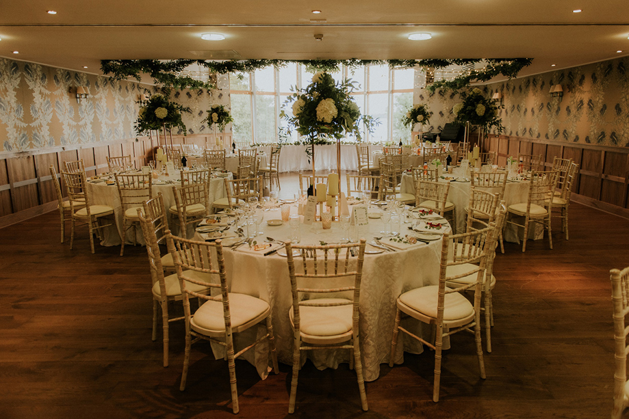Wedding meal set up with Chiavari chairs and flower stands as centerpieces.