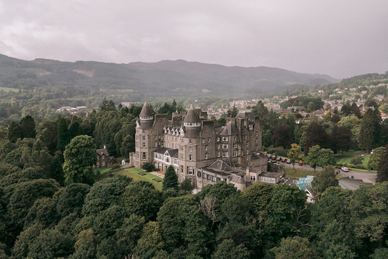 View of Atholl Palace Hotel from above with a drone, displaying its surrounding woodlands and hills in background of Pitlochry.