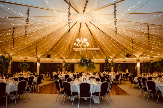 Elegant wedding reception venue decorated with fairy lights, round tables, and floral centrepieces inside the grand marquee-style Atholl Suite at Atholl Palace Hotel in the Scottish Highlands.