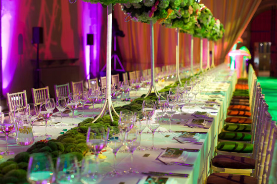 Green-hued room with mossy decor and small trees lining the long table