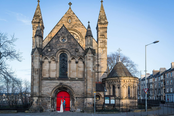 Couple look at each other outside red doors of Mansfield Traquair