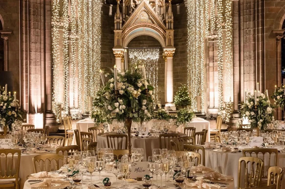 Wedding reception set up inside Mansfield Traquair Edinburgh with fairy lights, gold chairs and white floral centrepieces