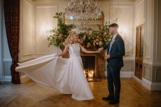 Bride and groom dancing by the fireplace in an elegant chandelier room at Auchen Castle.