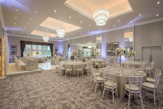 Wedding meal set up with white crystal chandeliers and flowers on round tables