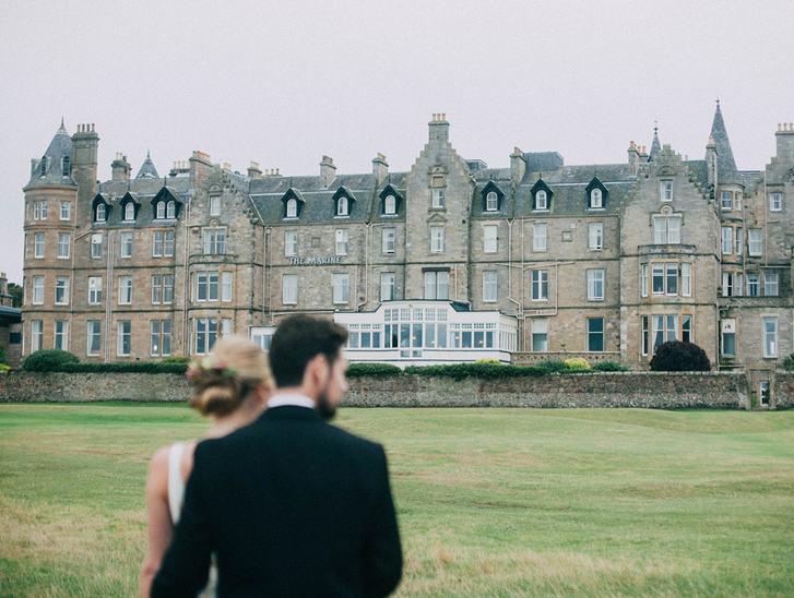 Couple walking on the lawn in front of Marine North Berwick hotel wedding venue in Scotland