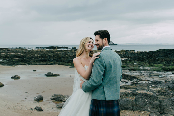 Newlyweds posing on the beach near Marine North Berwick with rocky shoreline and sea backdrop