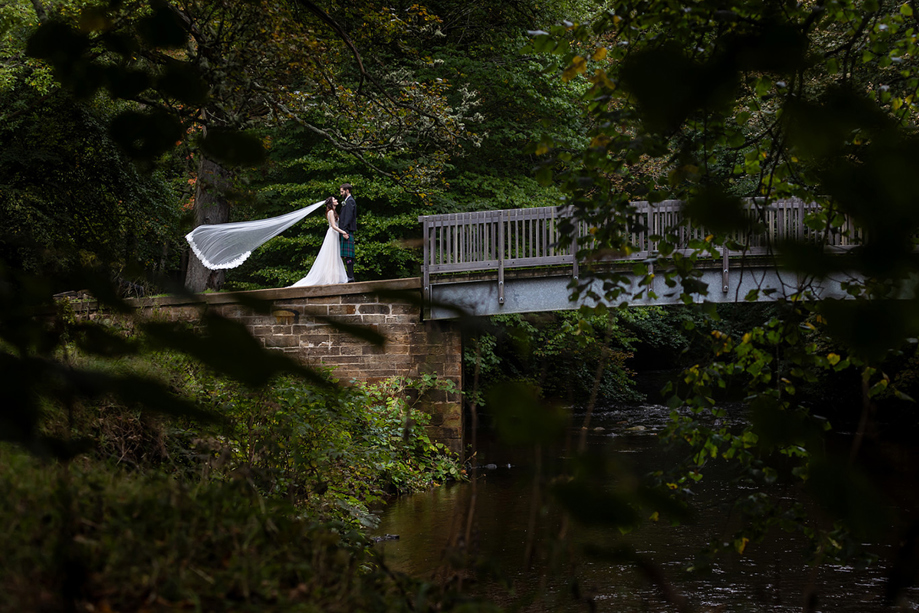 Bride and groom portrait on a bridge in the woodland grounds at Melville Castle.
