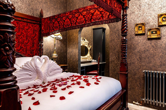 Castle Suite bedroom at Melville Castle with four-poster bed, rose petals and romantic decor.