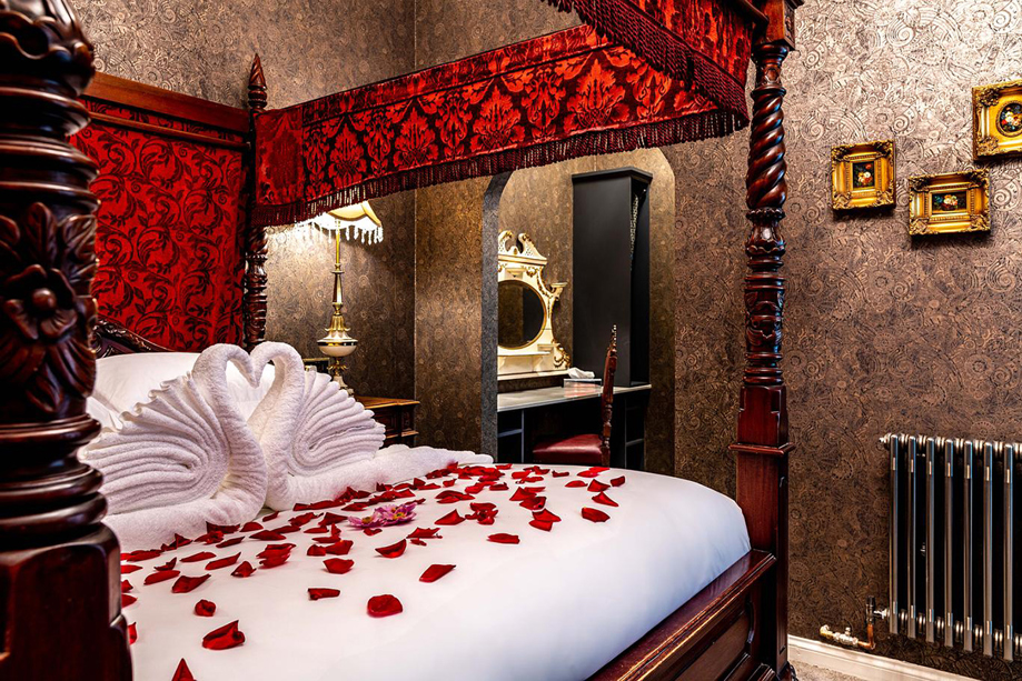 Castle Suite bedroom at Melville Castle with four-poster bed, rose petals and romantic decor.