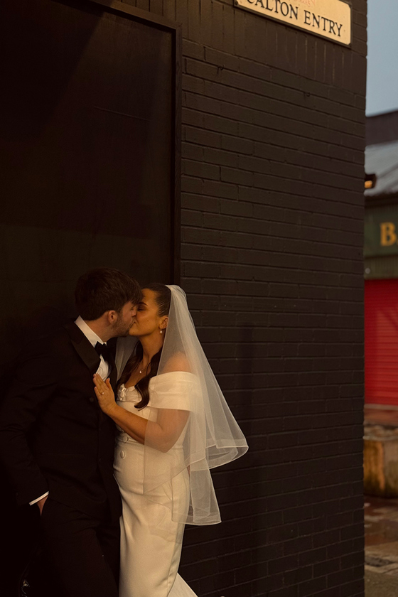 Bride and groom share a kiss on the corner of Calton Entry in the Barra's.