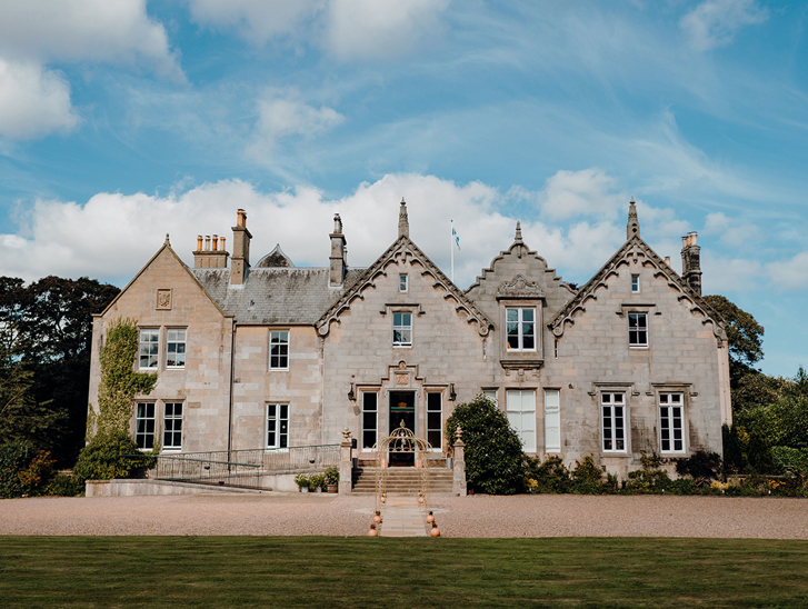 Exterior of Netherbyres House wedding venue in the Scottish Borders with blue skies and historic stone façade