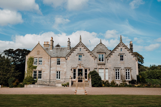 Exterior of Netherbyres House wedding venue in the Scottish Borders with blue skies and historic stone façade
