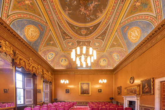 Ornate Drawing Room at Newbattle Abbey College with decorative ceiling and red chairs set for wedding ceremony
