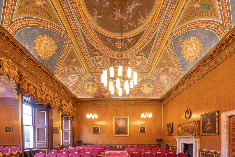 Ornate Drawing Room at Newbattle Abbey College with decorative ceiling and red chairs set for wedding ceremony