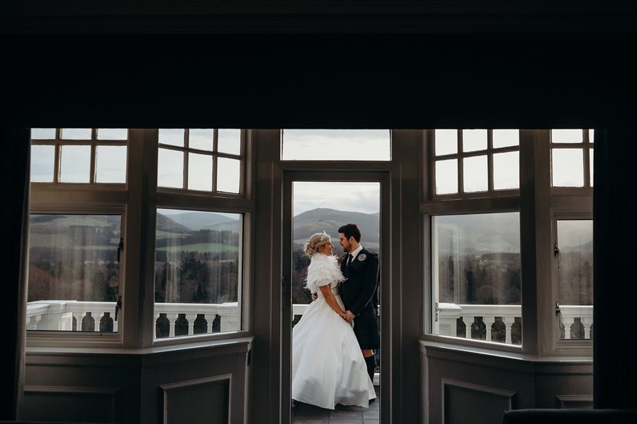 View of doorway to balcony with bride and groom looking at each other outside